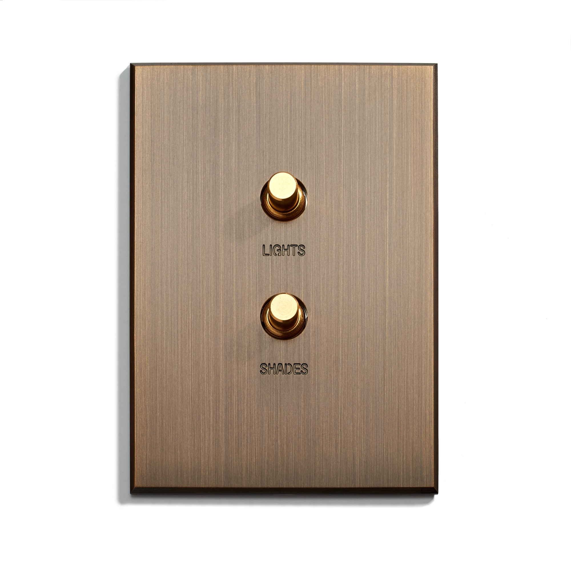 A sleek, modern wall switch panel with two brass knobs, labeled "lights" and "shades," against a brushed metallic background.