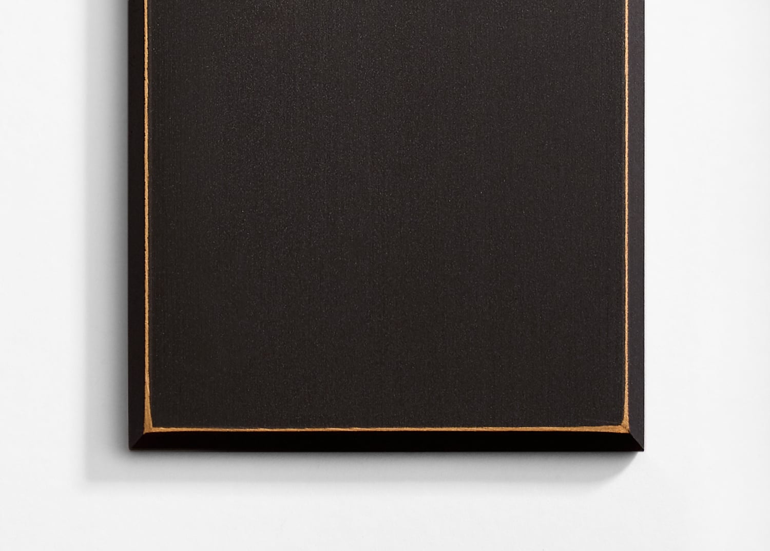 A black and gold painting on a white wall.