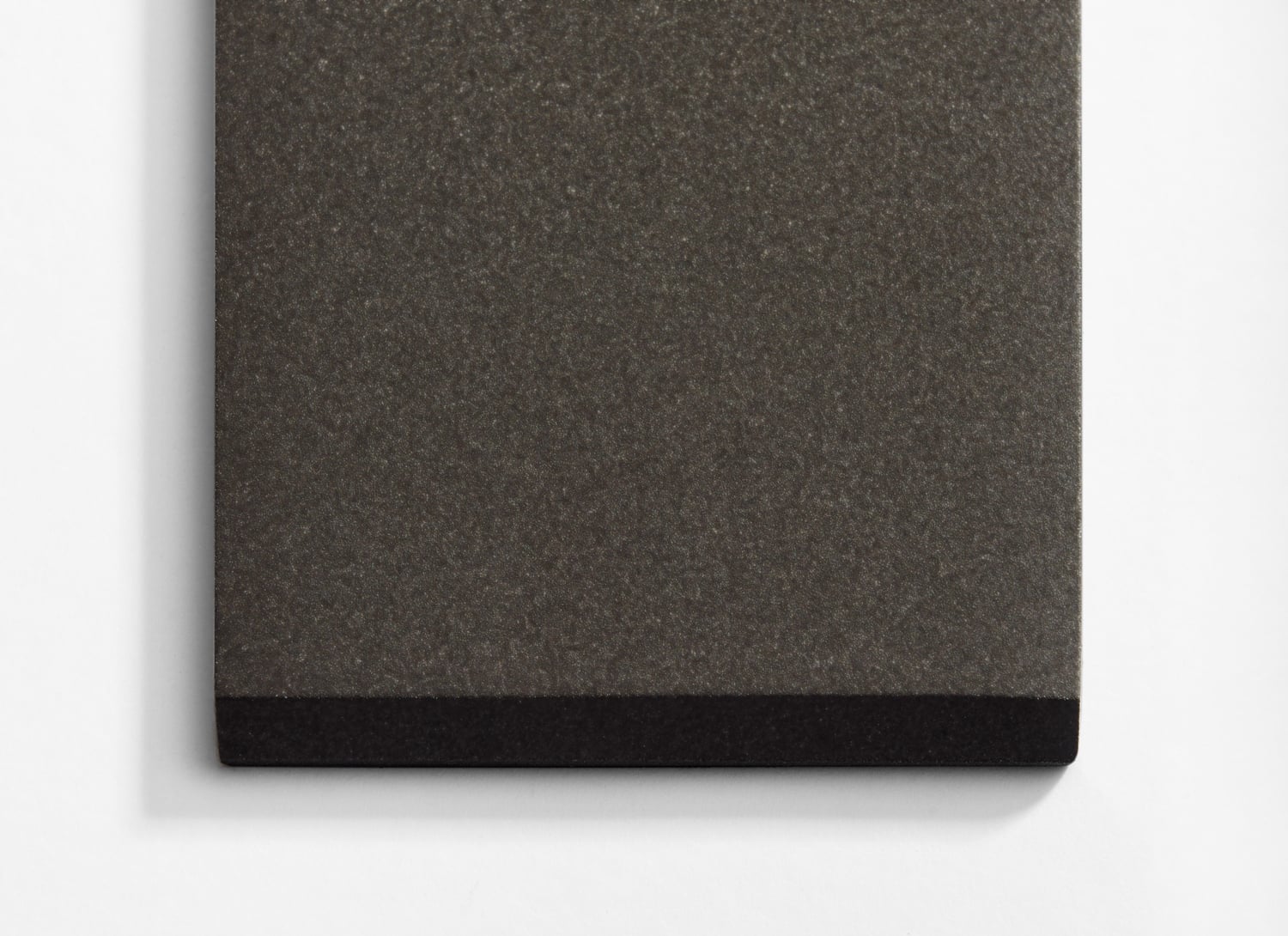 A grey notebook with black trim on a white surface.