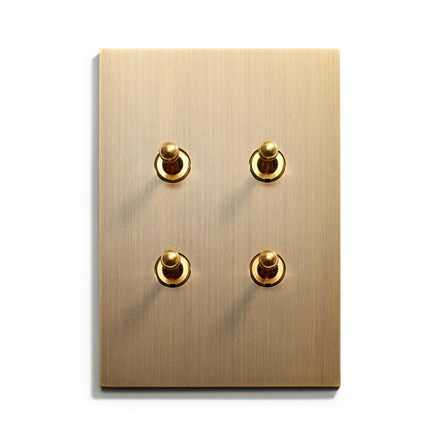 A gold wall plate with four switches on it.