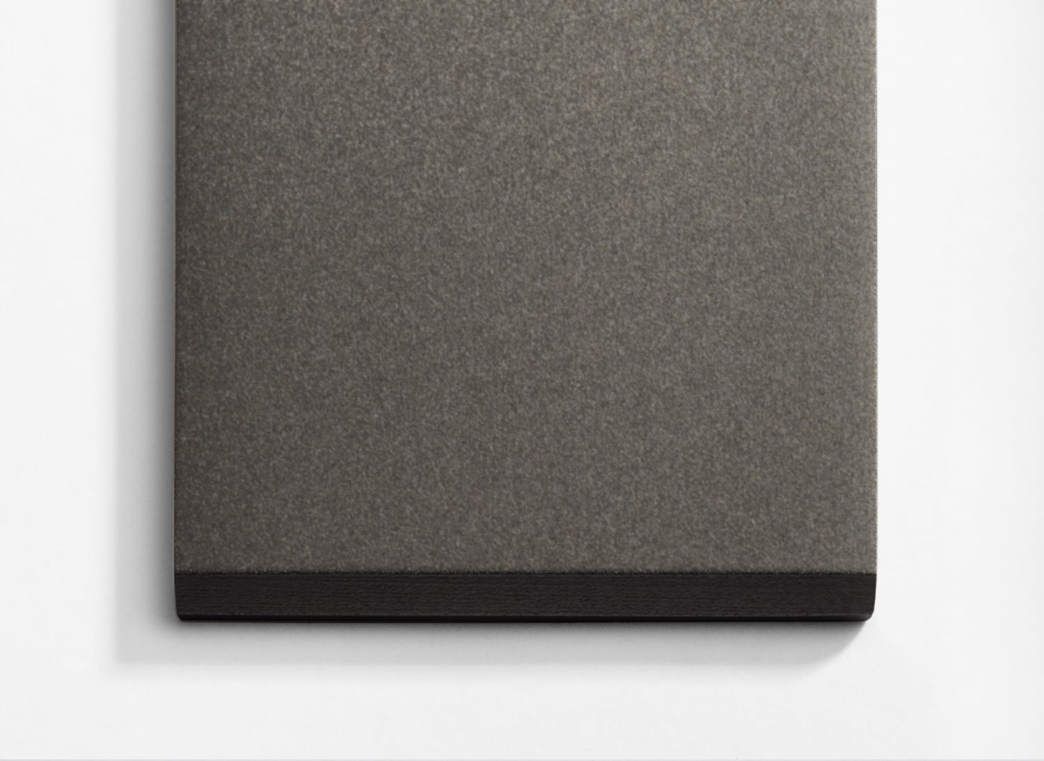 A grey and black notebook on a white surface.