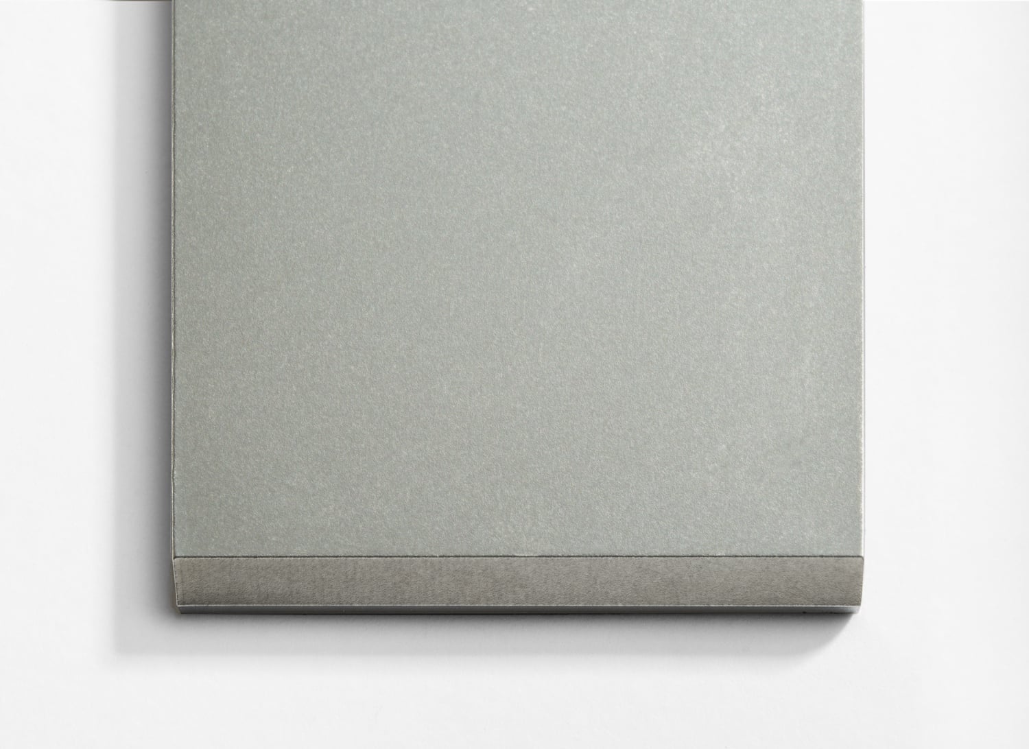 A grey notebook sitting on a white surface.