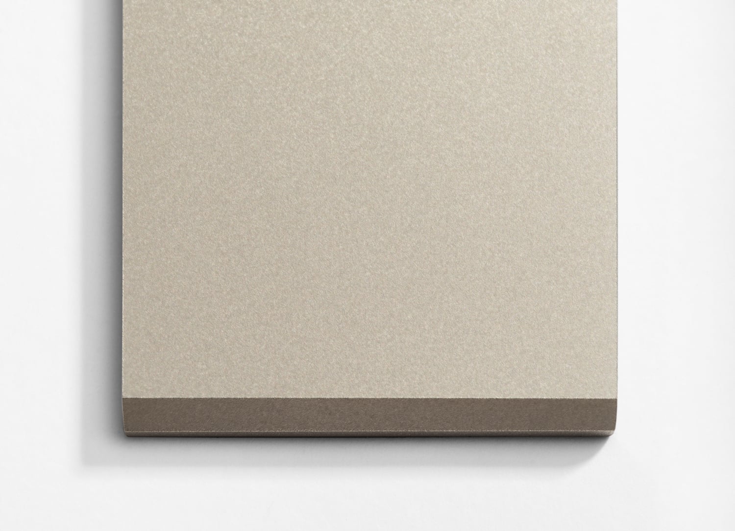 A beige notebook on a white wall.