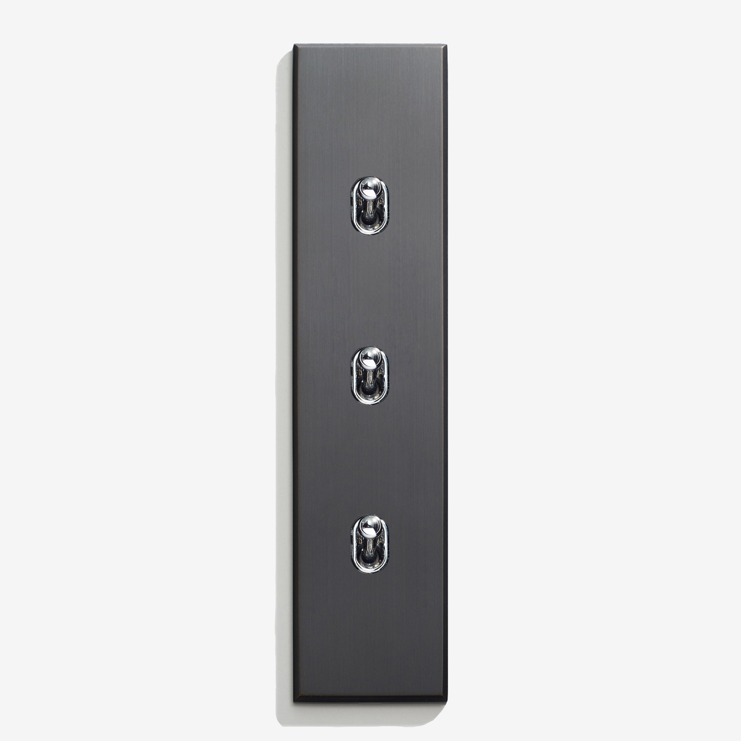 A modern, sleek, vertically-oriented light switch plate with three toggle switches on a white background.