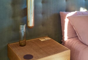 A wooden nightstand next to a bed.