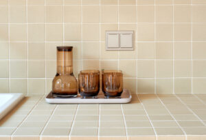 A kitchen sink with a tray of glasses and a light switch.