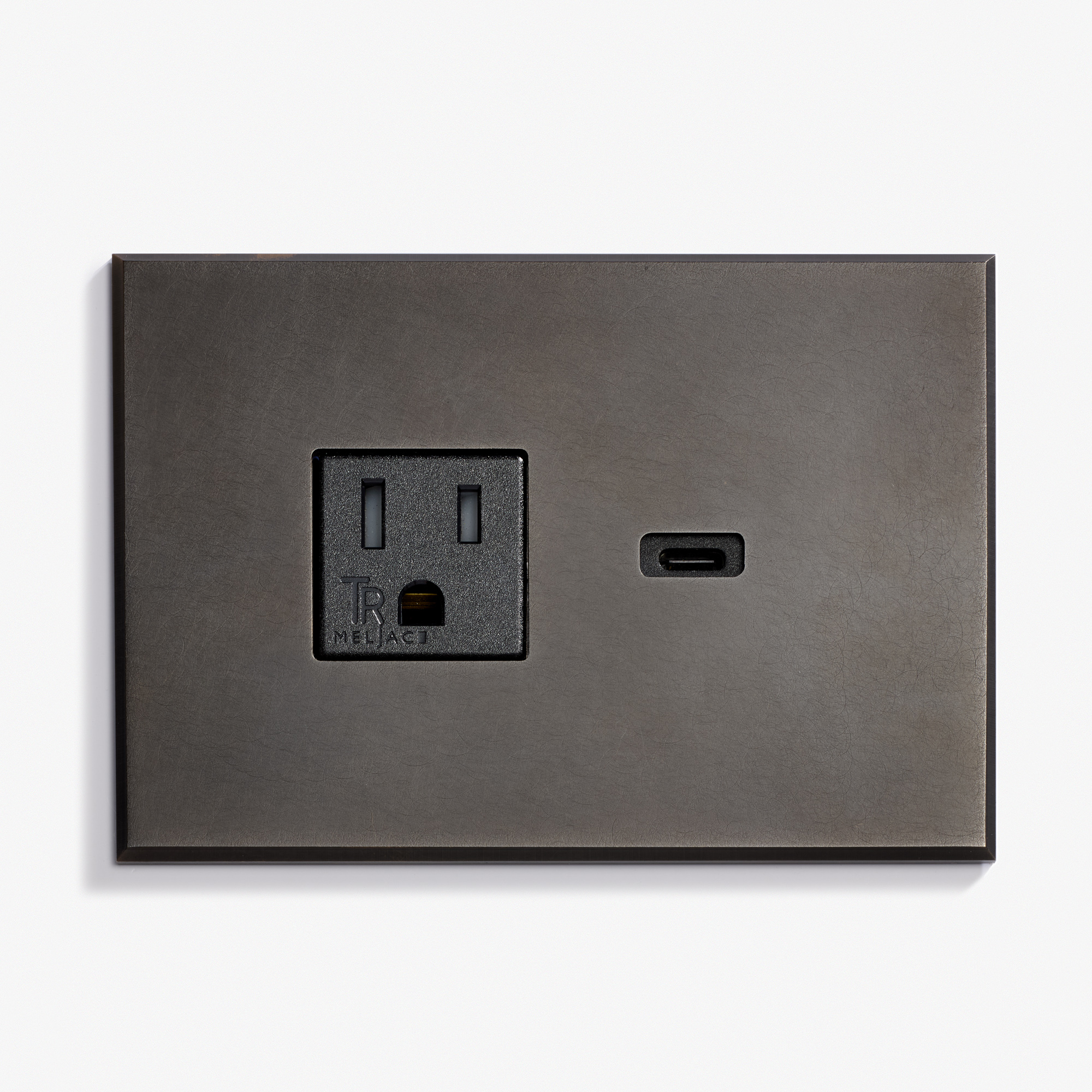 A dark gray wall plate features a standard three-prong electrical outlet on the left and a USB-C port on the right, both set against a light background.