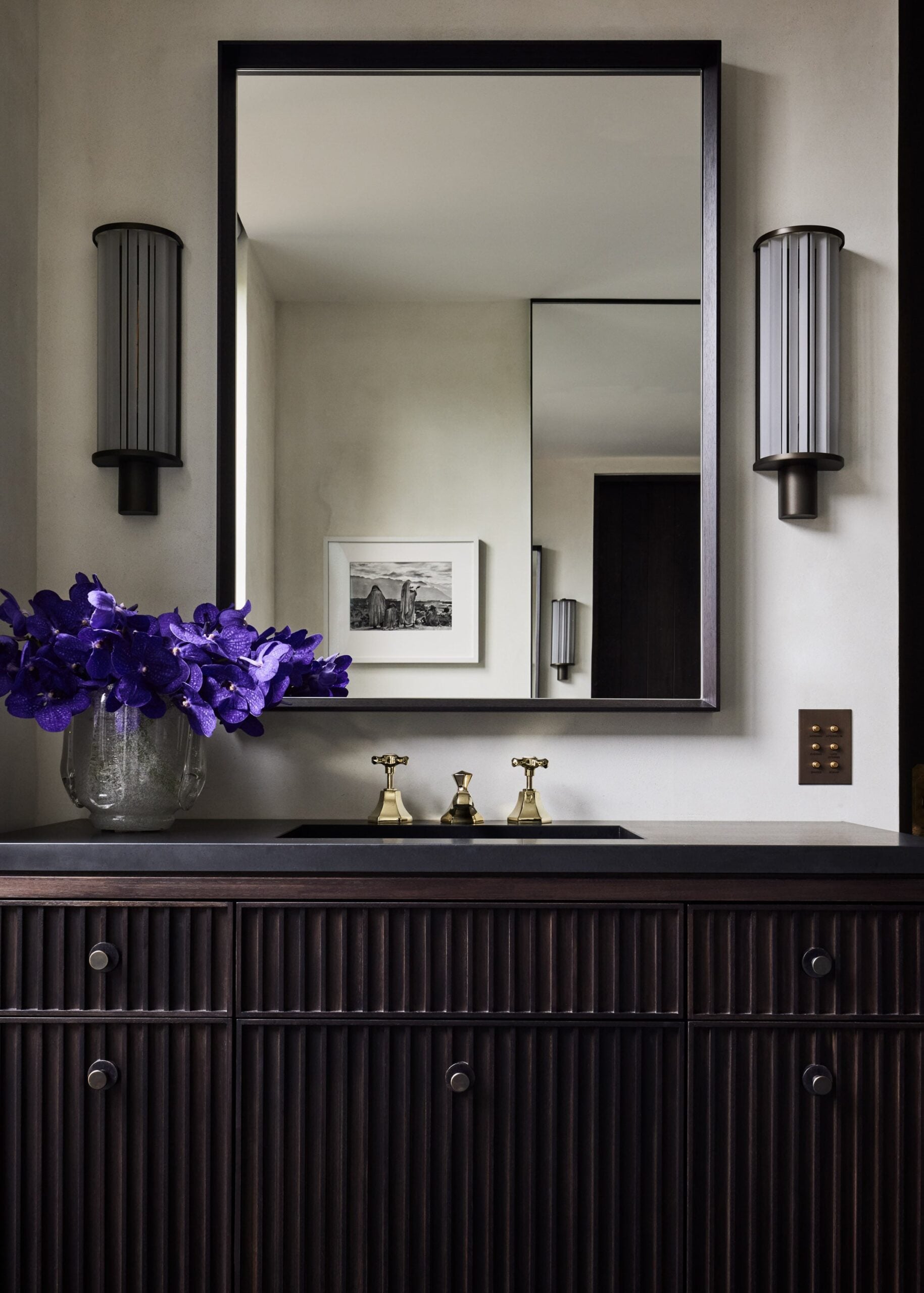 A bathroom vanity with purple flowers and a mirror.