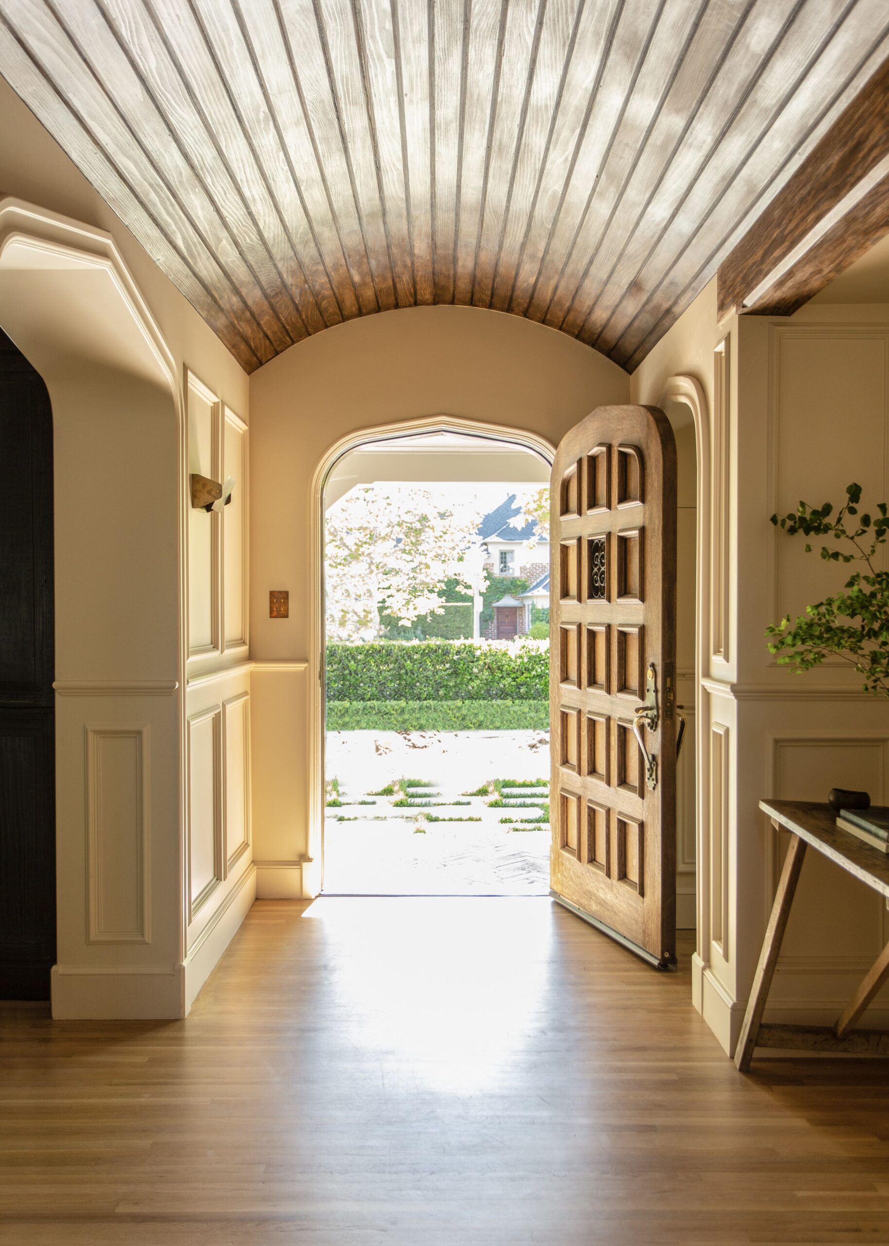 A hallway with a wooden door and a wooden ceiling.