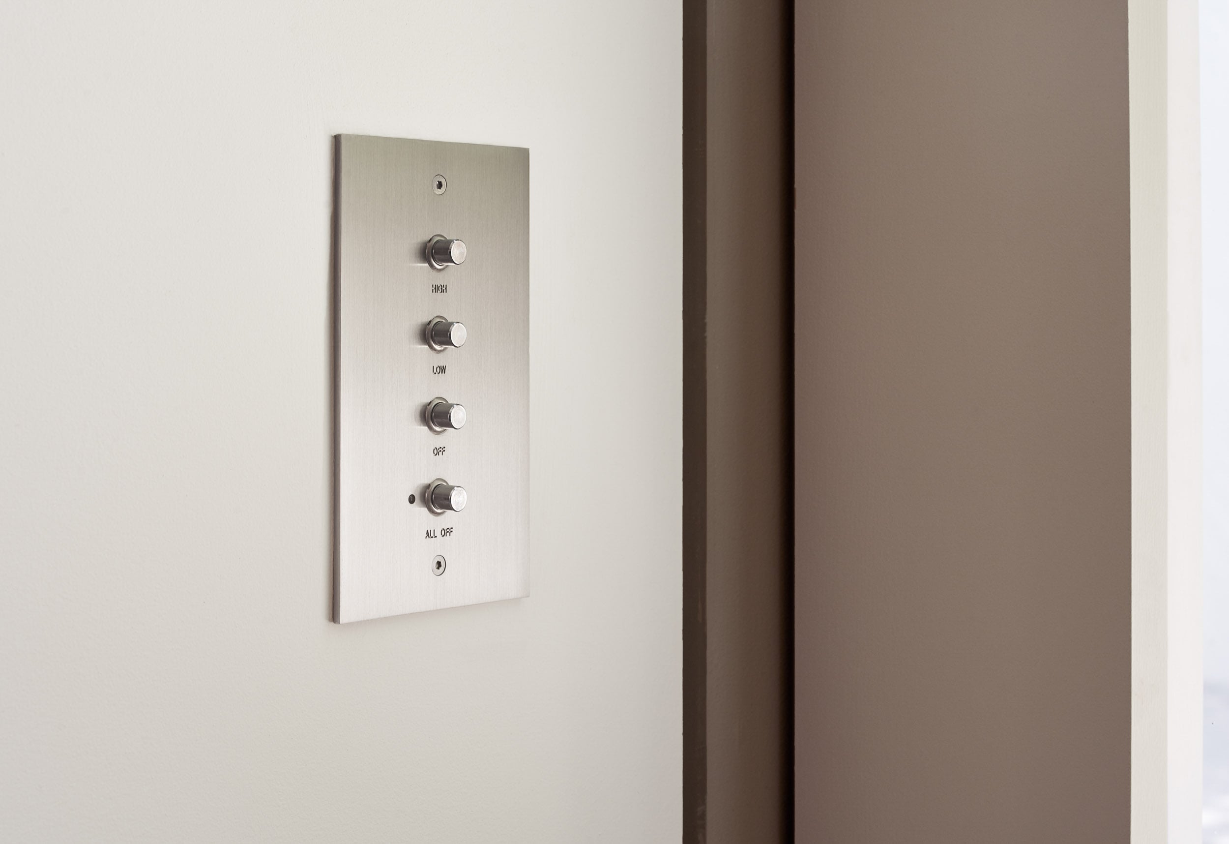 A white wall mounted control panel with four buttons.