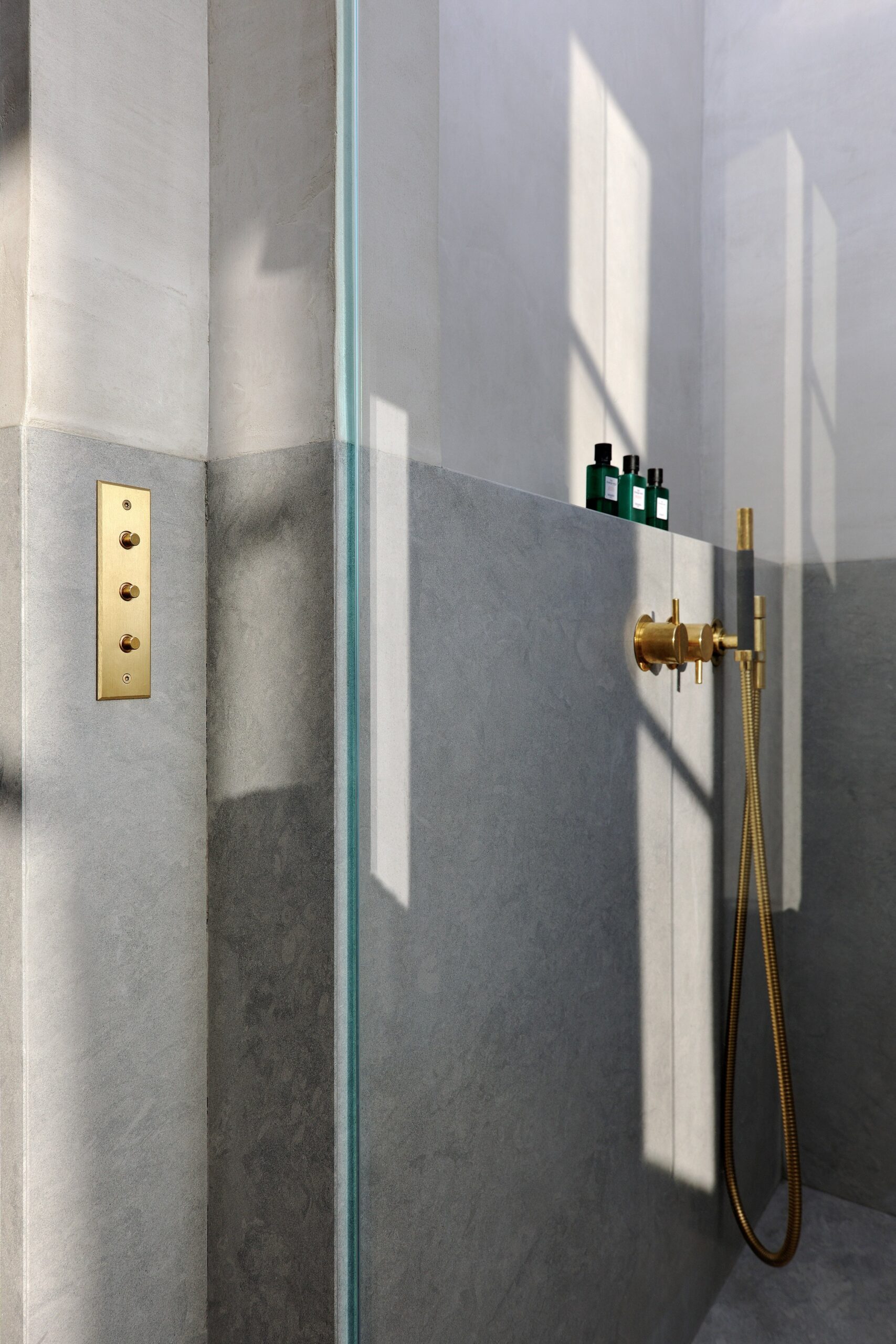 A bathroom with a glass shower and a gold shower head.