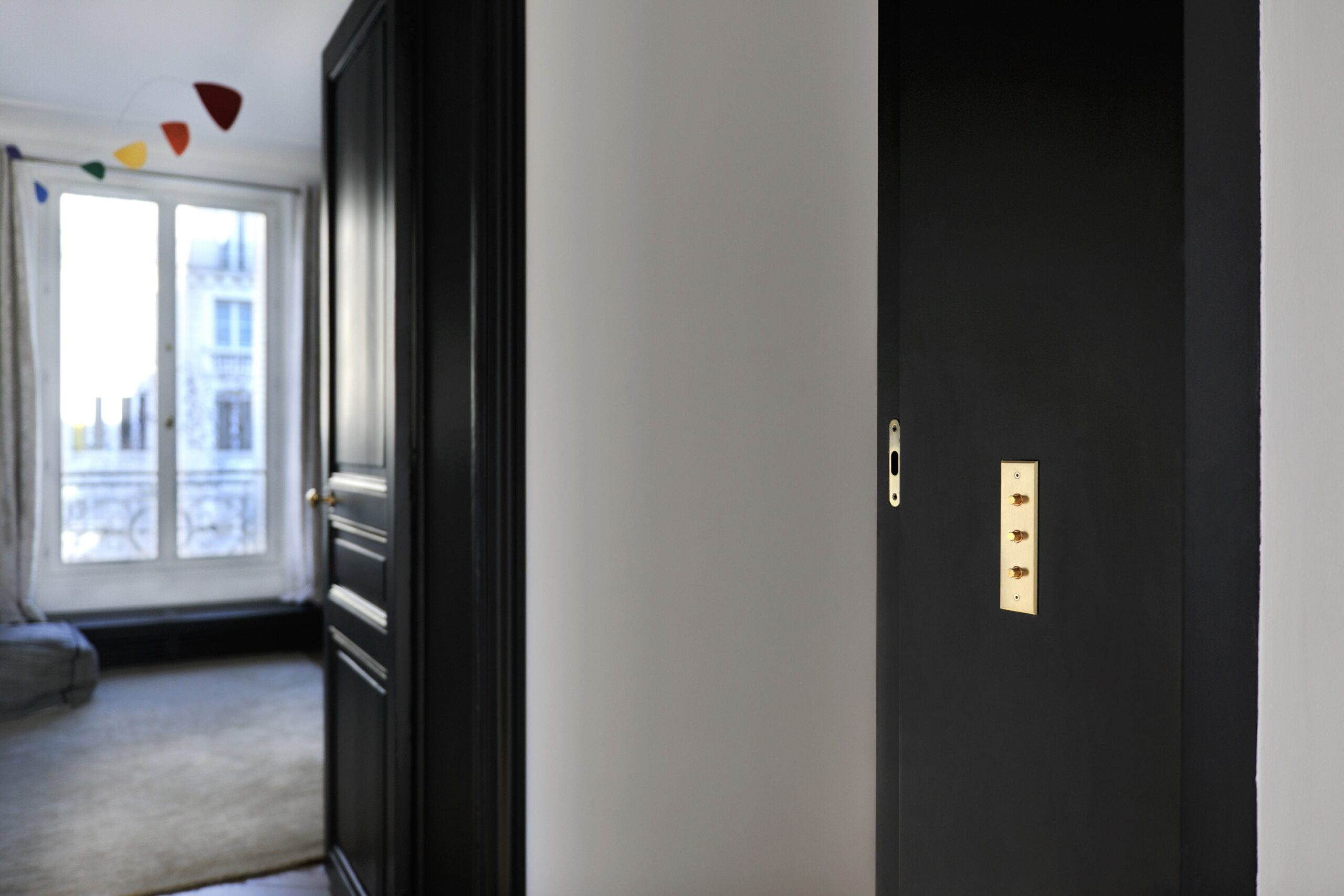 A black door in a room with a window.