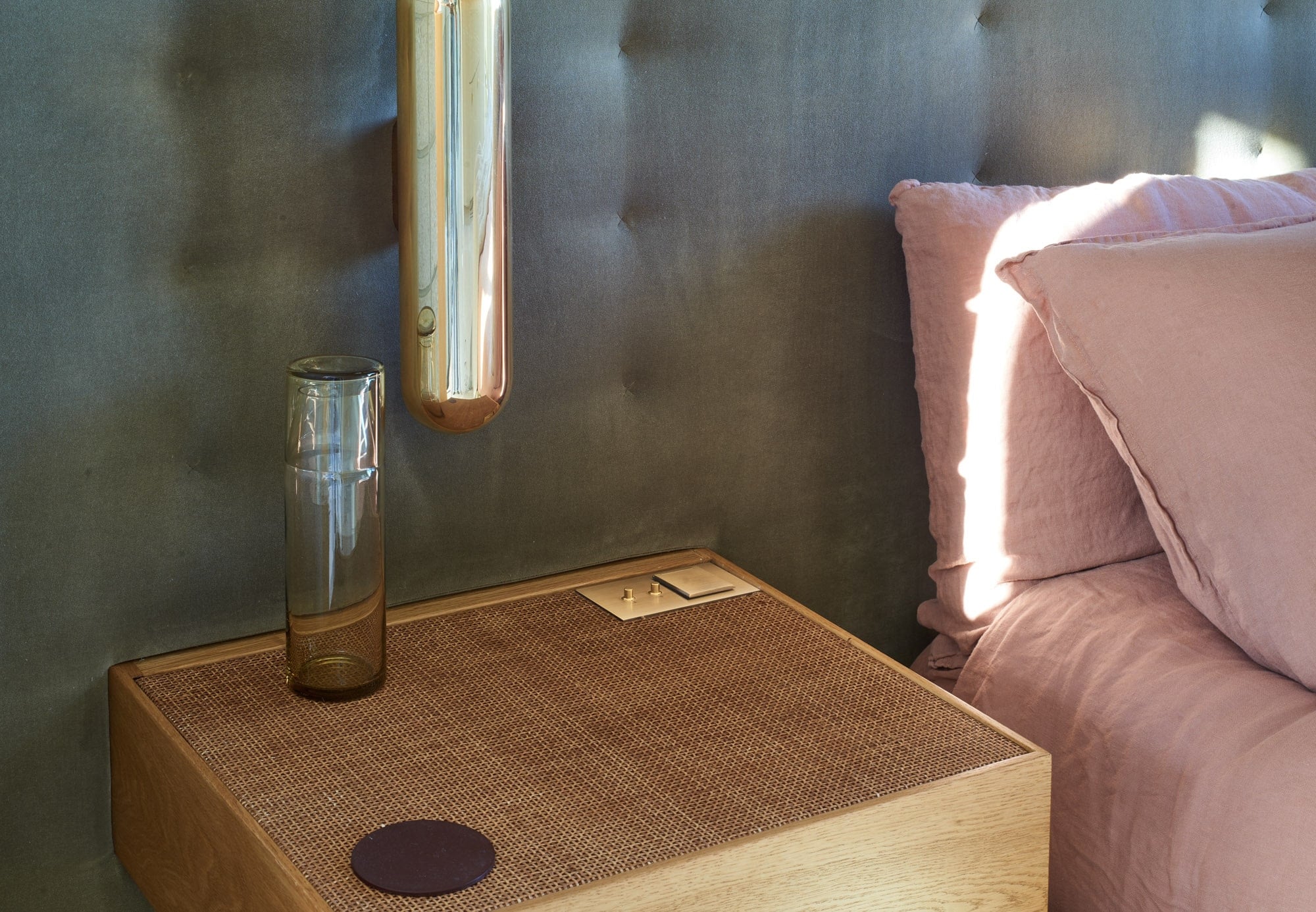 A wooden nightstand next to a bed.