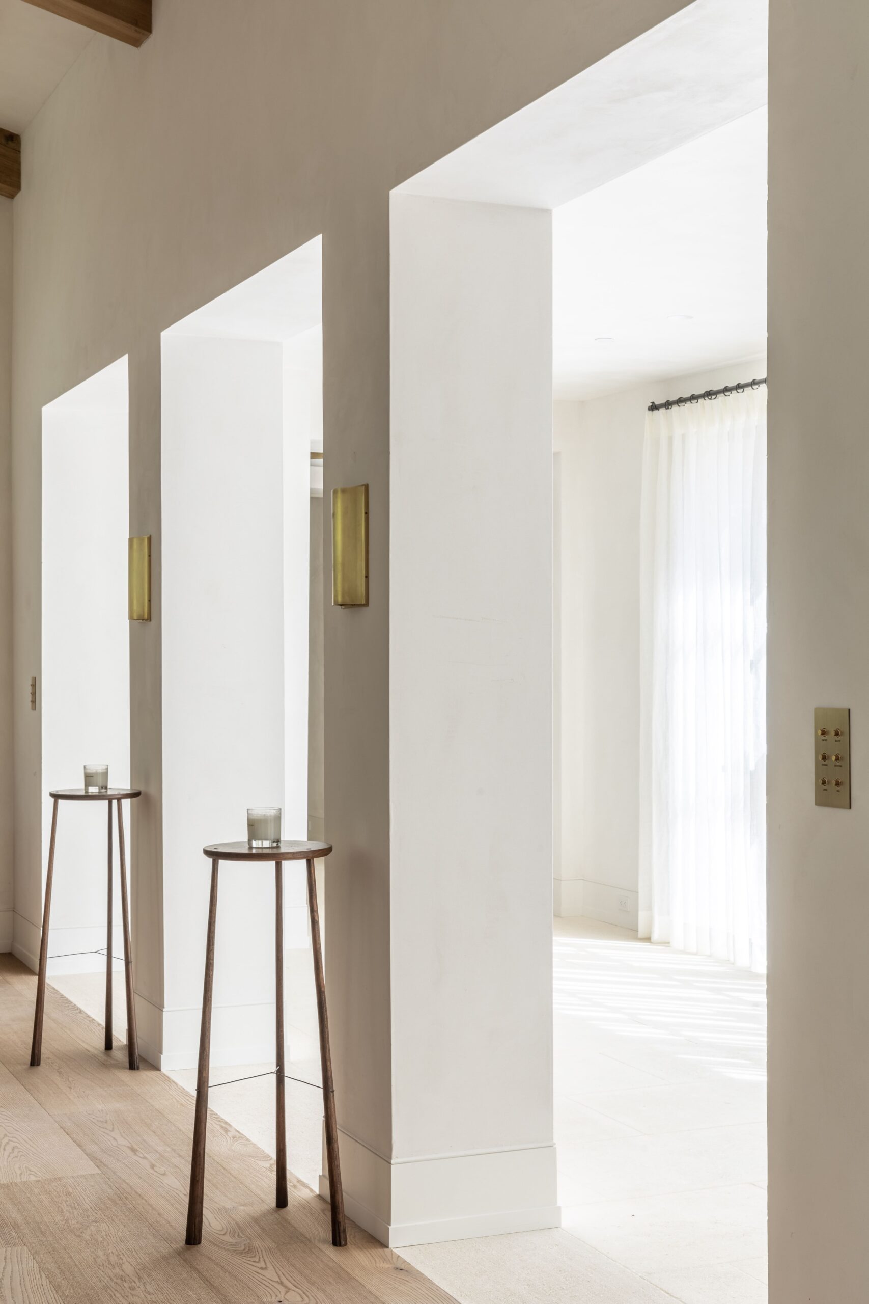 A hallway with white walls and wooden pillars.