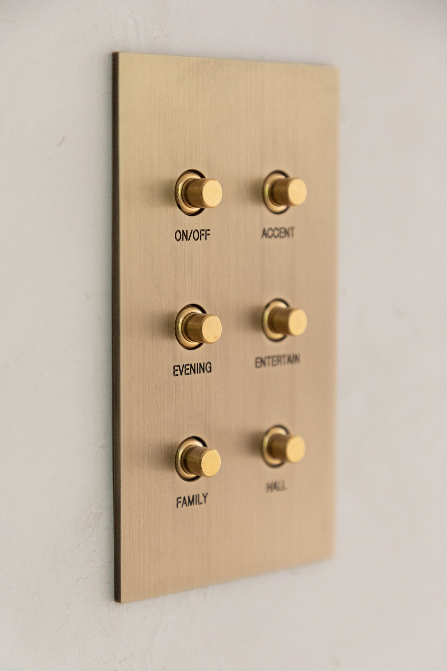 A brass wall switch panel with a number of buttons on it.