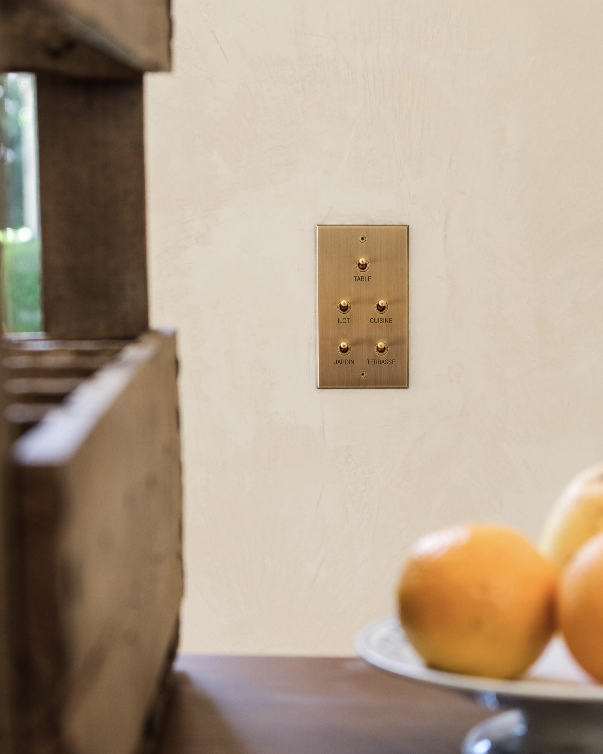 A crate of oranges on a wall next to a light switch.