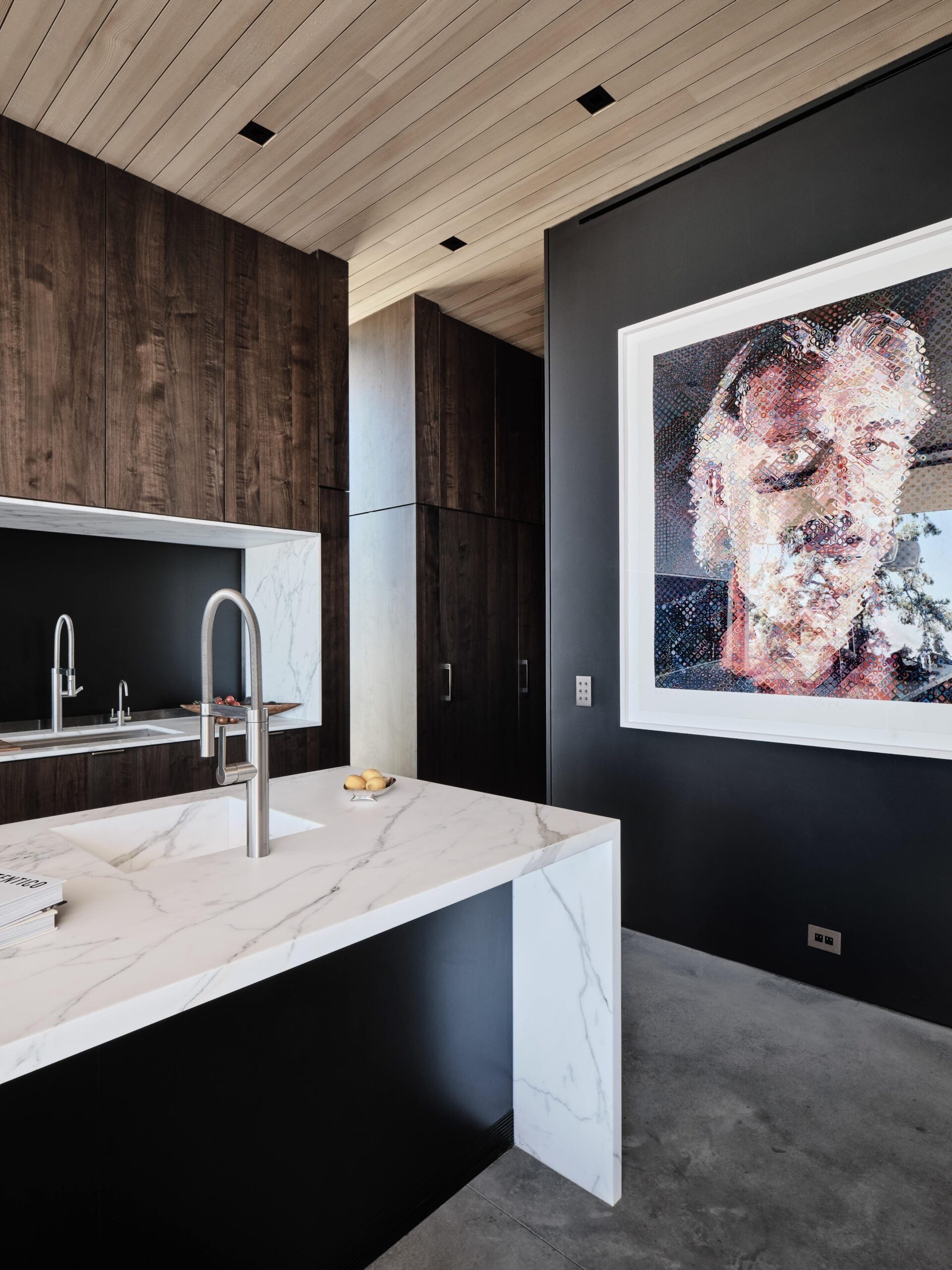 A black and white kitchen with a painting on the wall.