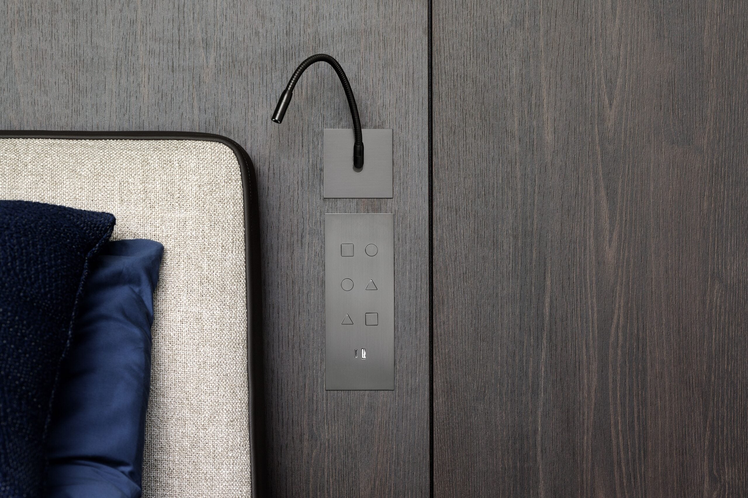 A bed with a blue pillow and a black headboard.