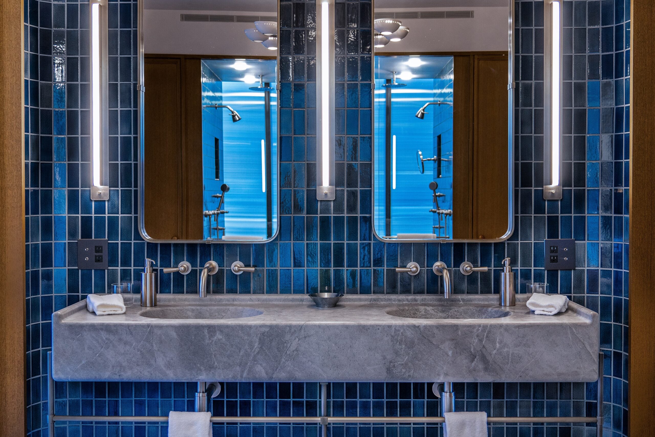 A bathroom with two sinks and blue tiled walls.