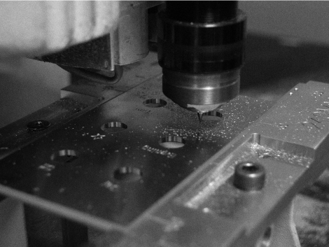 Close-up of a machine drilling holes in a metal piece.