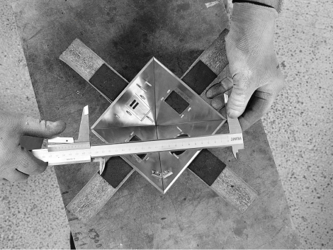 A person measuring a piece of metal with a ruler.