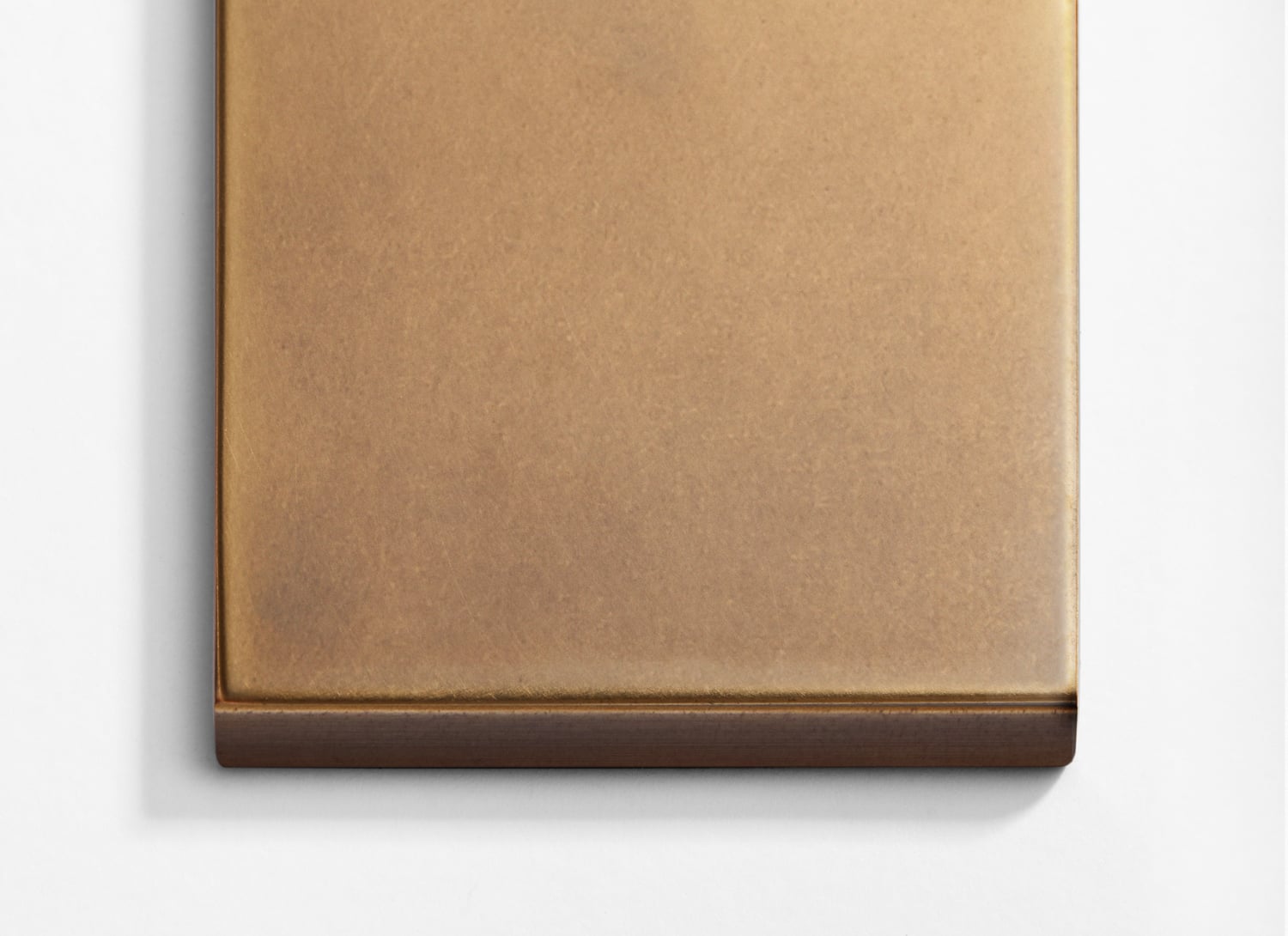 A small square of brass on a white surface.