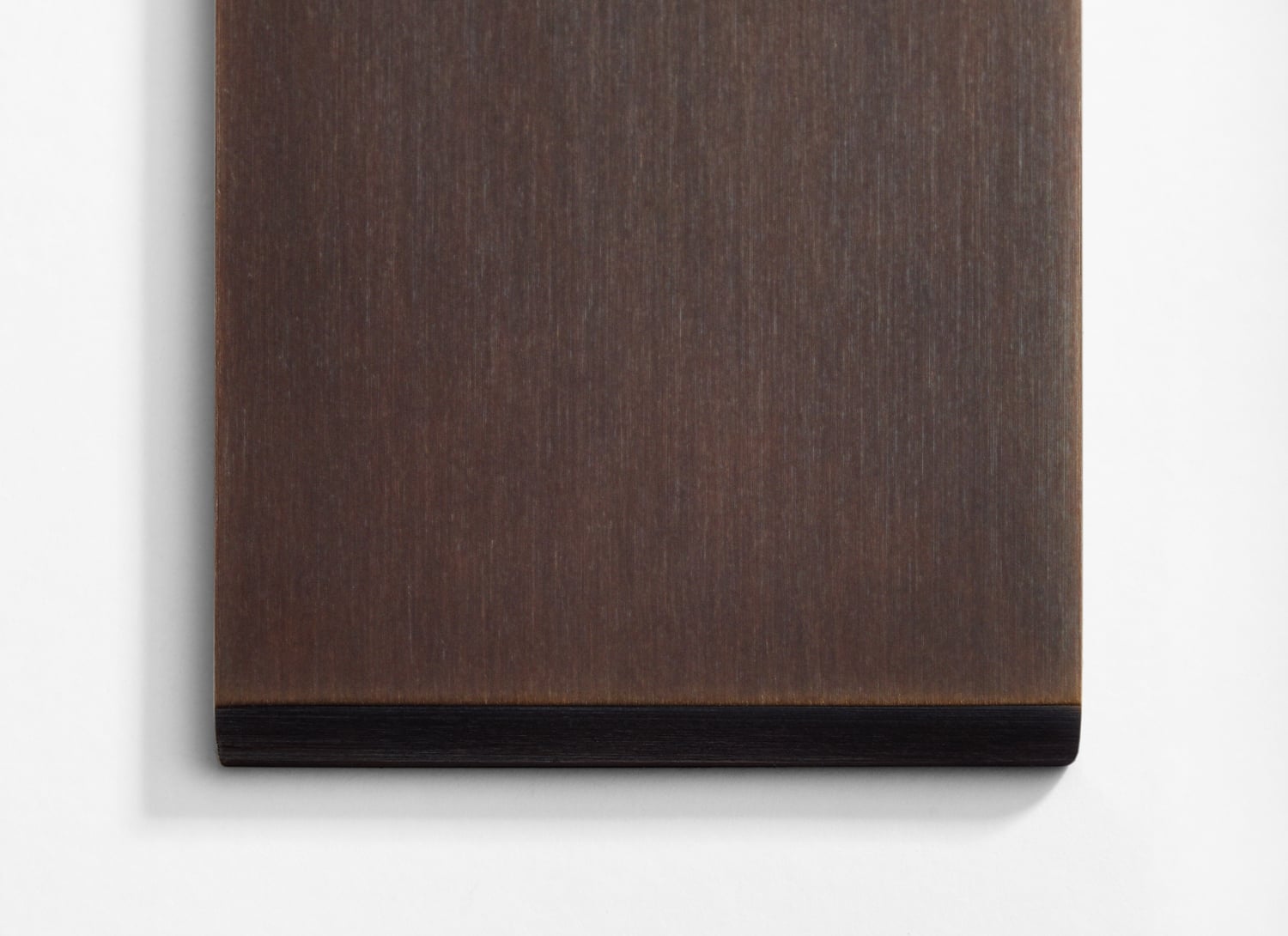 A brown wooden plate on a white wall.