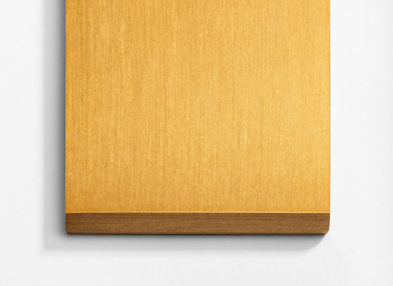 A yellow piece of wood on a white wall.