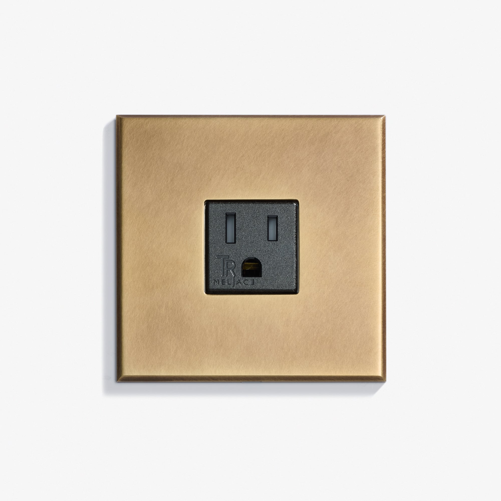 A single black electrical outlet with a brass-colored square faceplate mounted on a white wall.
